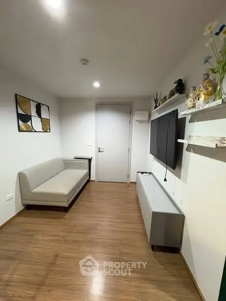 Modern living room with sleek design and wooden flooring, featuring a stylish sofa and wall-mounted TV.