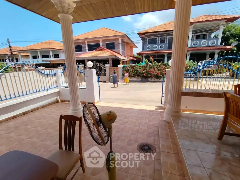 Charming patio view with elegant columns and neighborhood houses in a serene residential area.