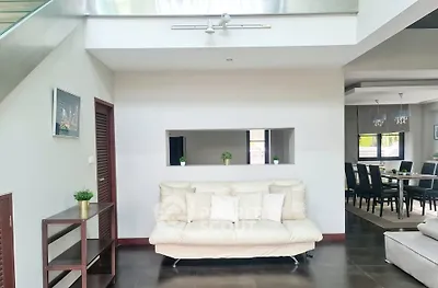 Modern living room with sleek design and open dining area, featuring elegant decor and natural light.