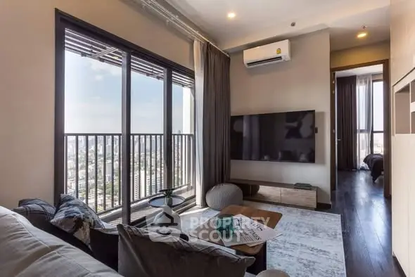 Modern living room with city view, large TV, and stylish decor in high-rise apartment.