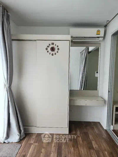 Modern bedroom with sleek wardrobe and air conditioning, featuring elegant wood flooring and stylish curtains.