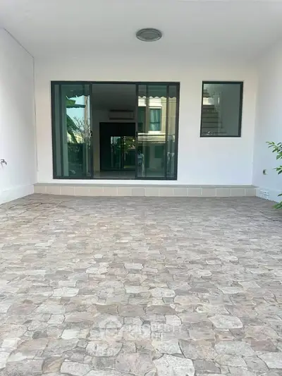 Spacious patio with stone flooring and large glass doors leading to the interior, perfect for outdoor relaxation.
