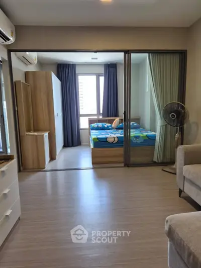 Modern apartment interior with bedroom and living area, featuring sleek design and natural light.