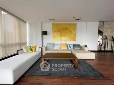 Spacious modern living room with stylish decor and large windows.