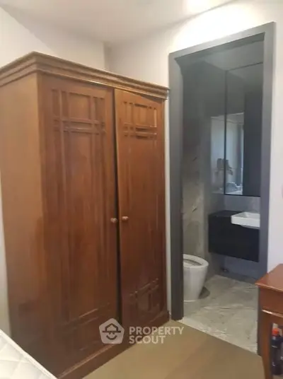 Cozy bedroom with wooden wardrobe and ensuite bathroom featuring modern fixtures.
