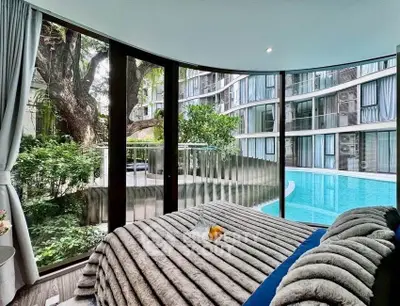 Luxurious bedroom with floor-to-ceiling windows offering stunning pool and garden views in modern apartment.