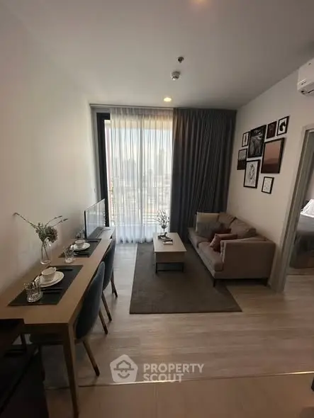 Modern living room with cozy seating and dining area, featuring large window with city view.