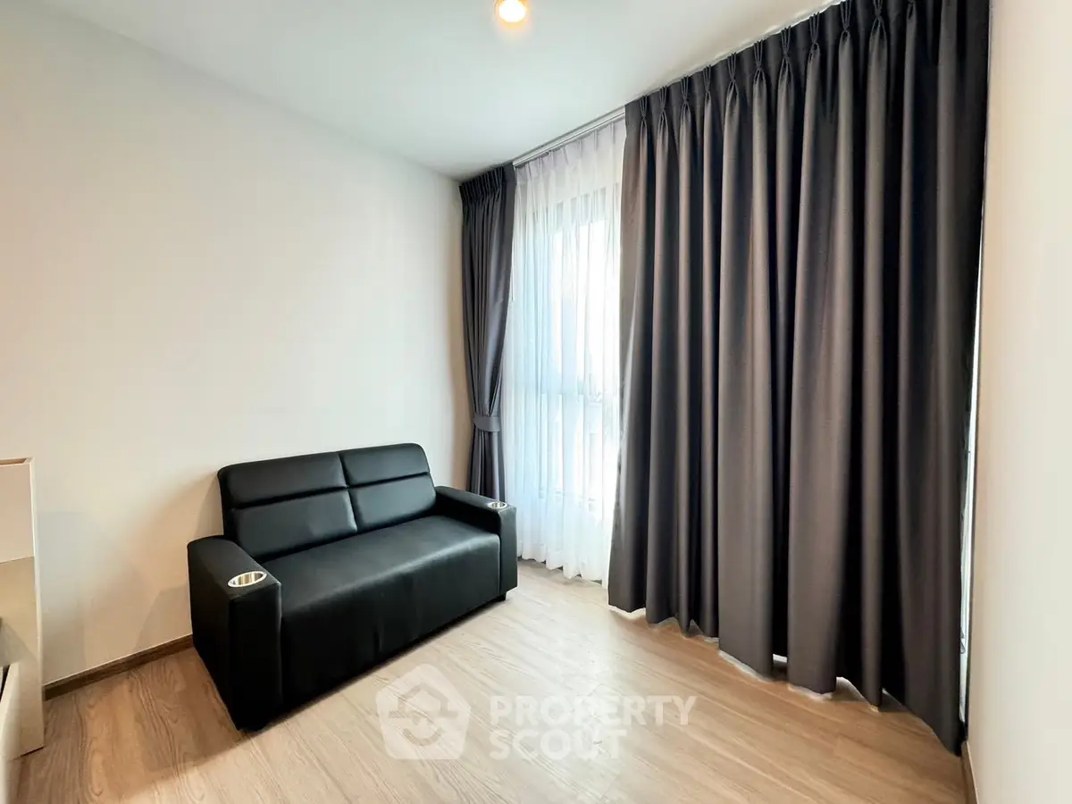 Modern living room with sleek black sofa and floor-to-ceiling curtains, perfect for cozy relaxation.