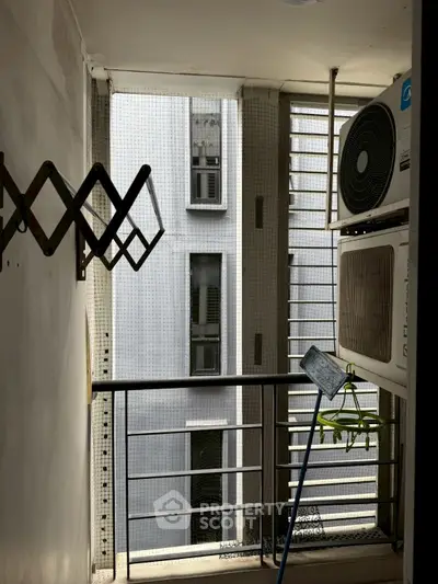 Compact balcony with air conditioning units and a view of neighboring building.