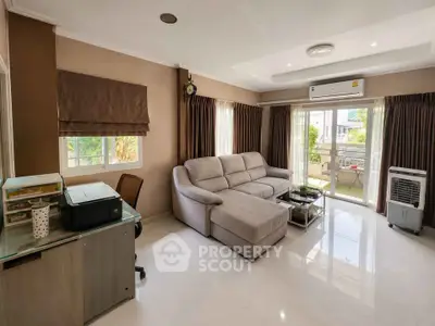 Spacious living room with modern sofa and natural light, featuring air conditioning and balcony access.