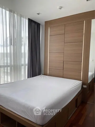 Modern bedroom with wooden accents and large window in a stylish apartment.