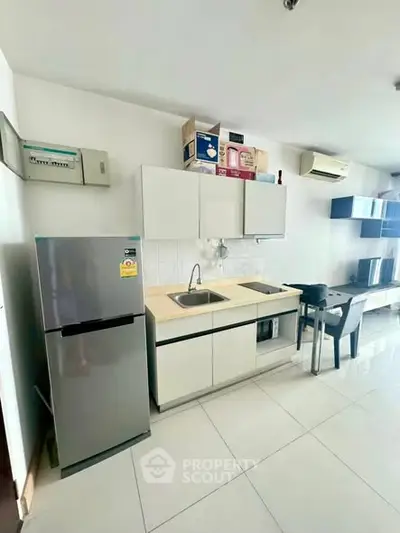 Modern kitchen with sleek cabinets, stainless steel fridge, and air conditioning in a bright open space.