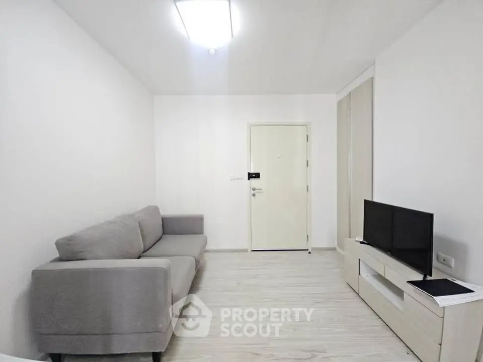 Modern minimalist living room with gray sofa and TV unit, bright and inviting space.
