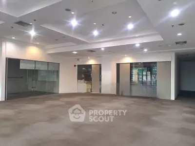 Spacious commercial interior with modern lighting and glass partitions, ideal for office or retail space.