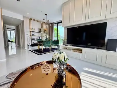 Luxurious living room with modern decor and large TV, featuring elegant furniture and abundant natural light.
