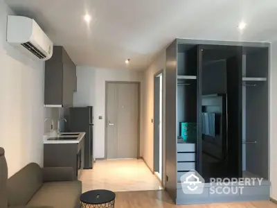 Modern studio apartment with sleek furniture and integrated appliances, featuring a compact kitchen, cozy living space, and ample natural light.