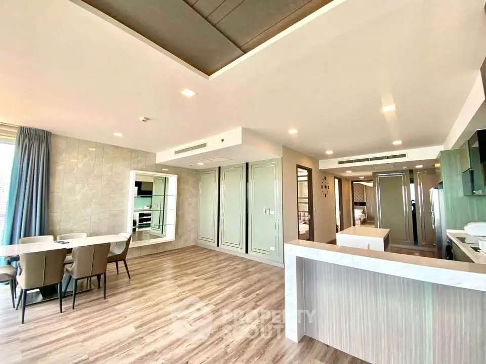 Spacious modern living room with open kitchen and elegant dining area, featuring stylish decor and ample natural light.