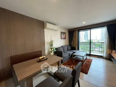 Modern living room with city view, featuring stylish furniture and large windows.