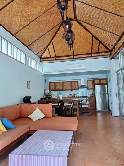 Spacious living room with high ceiling and modern kitchen in tropical style home.