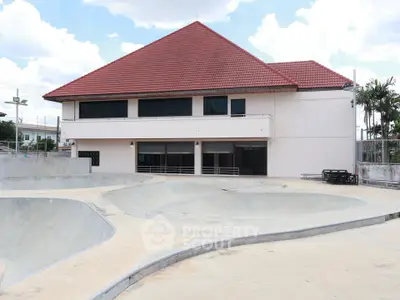 Modern building with red roof and skate park in front, perfect for urban lifestyle enthusiasts.