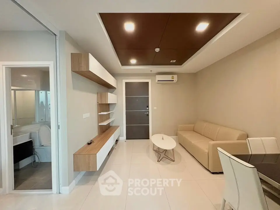 Modern living room with beige sofa, sleek wooden shelves, and elegant dining area in a contemporary apartment.