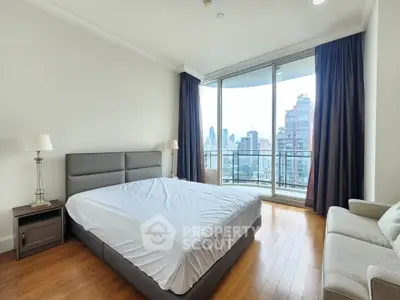 Spacious bedroom with city view and modern furnishings in high-rise apartment.