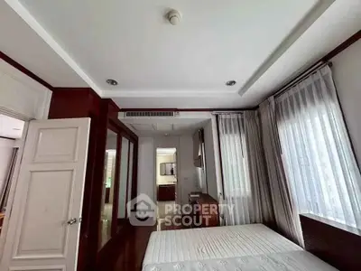 Spacious bedroom with elegant wooden accents and large windows for natural light.