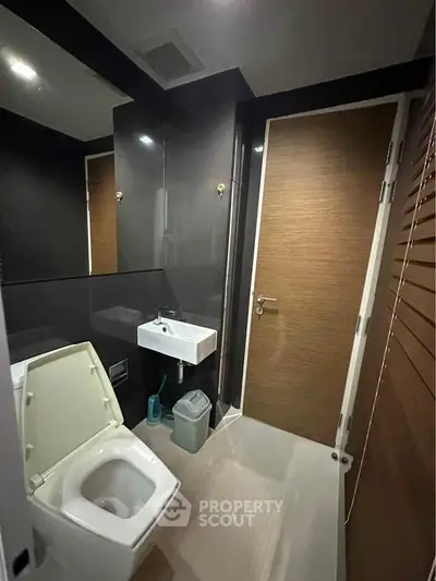 Modern bathroom with sleek design and compact layout, featuring a toilet and sink.