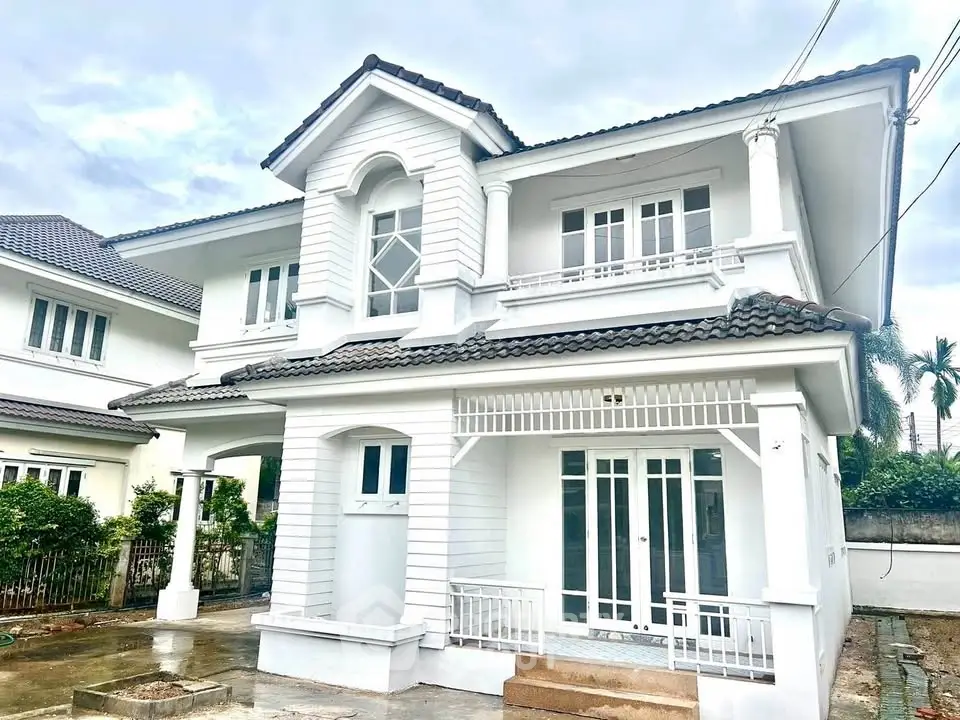 Charming two-story white house with classic architectural design and spacious front yard.