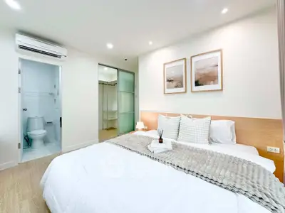 Spacious bedroom with ensuite bathroom and modern decor in a stylish apartment.