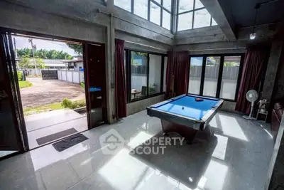 Spacious modern living room with pool table and large windows offering garden view.