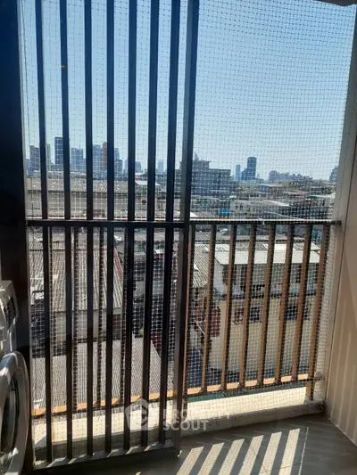 Urban balcony with city skyline view and safety netting, perfect for enjoying the cityscape.