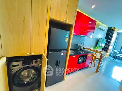 Modern kitchen with red cabinets, washing machine, and fridge in a stylish apartment.