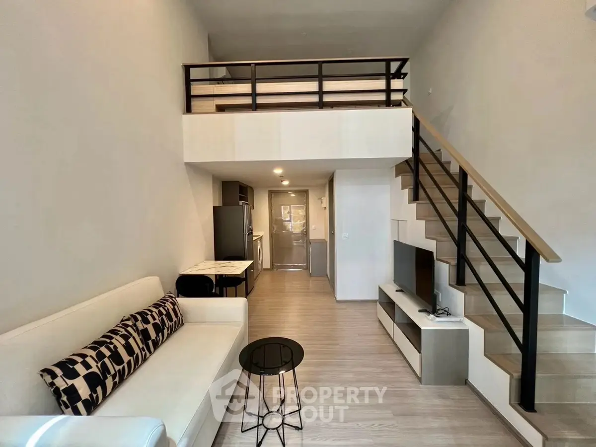Modern loft apartment with mezzanine, stylish living area, and sleek kitchen design.