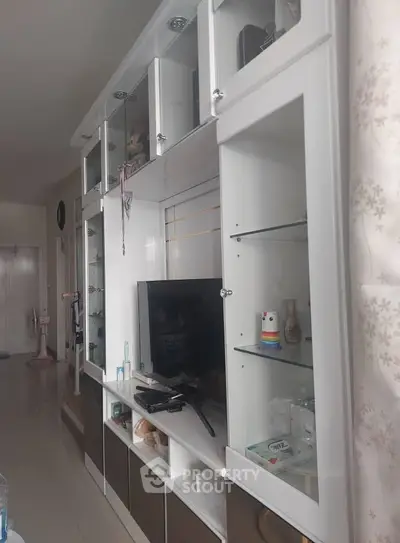 Spacious living room with modern white entertainment unit and TV, perfect for relaxation and entertainment.