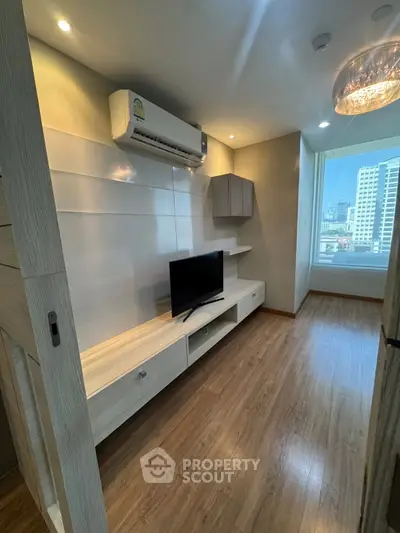 Modern living room with sleek design, featuring a mounted TV and air conditioning, offering city views.