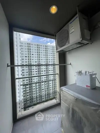 Modern balcony with city view and air conditioning unit in high-rise apartment.