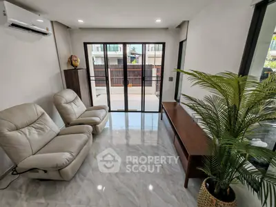 Modern living room with sleek furniture and large windows offering natural light and outdoor view.