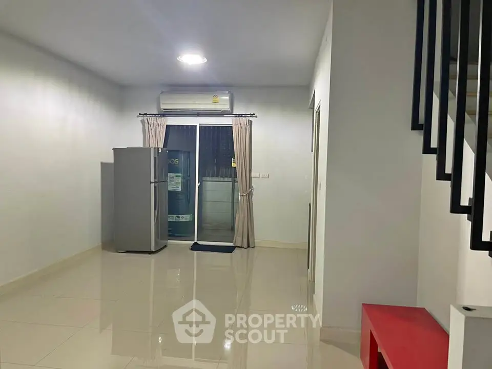 Spacious modern living area with sleek tiled flooring and large window for natural light.
