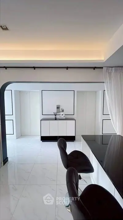 Modern kitchen with sleek black and white design, featuring high-gloss cabinets and stylish bar stools.