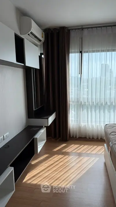 Modern bedroom with natural light, featuring sleek furniture and air conditioning, perfect for urban living.