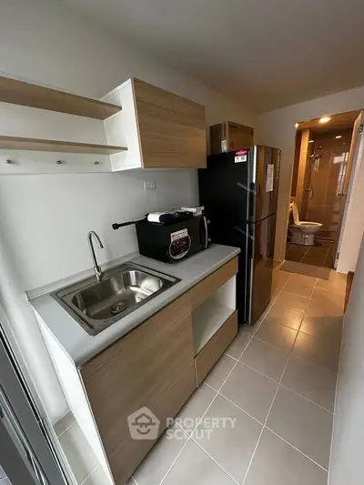 Modern compact kitchen with sleek cabinetry and stainless steel appliances in a cozy apartment.