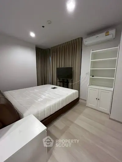Modern bedroom with sleek design, featuring a comfortable bed, built-in shelves, and air conditioning.