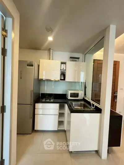 Modern compact kitchen with sleek white cabinets and stainless steel appliances