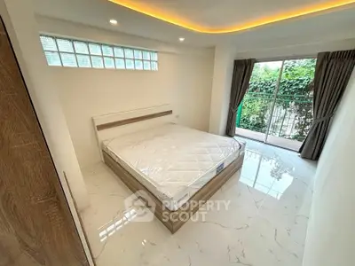 Modern bedroom with large window and balcony access, featuring sleek design and natural light.