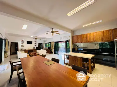 Spacious open-plan living and dining area with wooden furniture and modern kitchen.