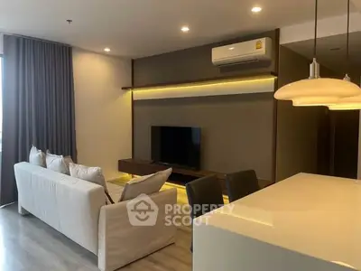 Modern living room with sleek design, featuring a wall-mounted TV and stylish lighting.