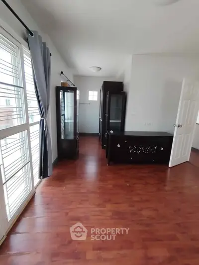 Spacious room with wooden flooring and large windows, perfect for natural light.