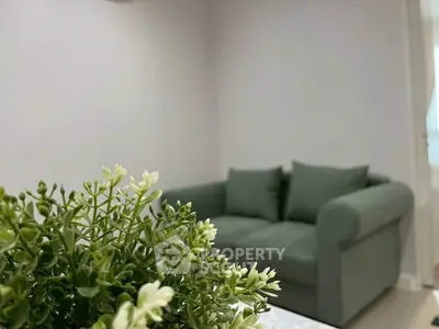 Cozy living room with green sofa and decorative plant, perfect for relaxation.