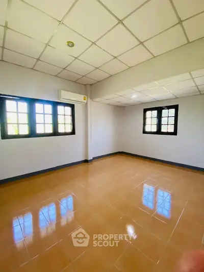 Spacious empty room with tiled floor and large windows, perfect for customization.